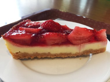 Beyaz tabakta çilekli cheesecake dilimi.