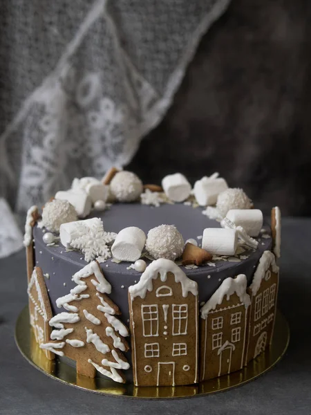 Christmas gray cake decoraited of gingerbread cookies in shape of homes and snowy christmas trees, marshmallows, snowflakes, sweets. Christmas, New Year greeting card. Gray background. Copy space. — Stock Photo, Image