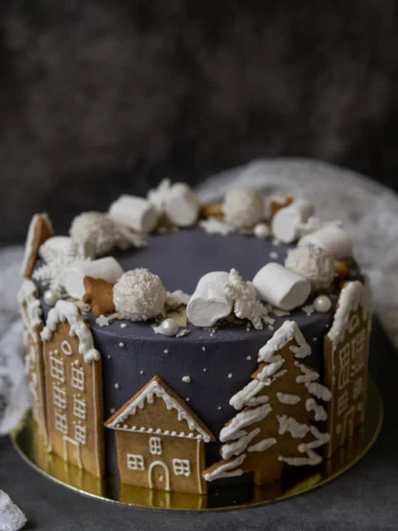Pastel gris navideño decorado con galletas de jengibre en forma de casas y árboles de Navidad nevados, malvaviscos, copos de nieve, dulces. Navidad, tarjeta de felicitación de Año Nuevo. Fondo gris. Copiar espacio . — Foto de Stock