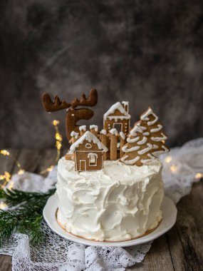 Noel pastası ve zencefilli kurabiye ev şeklinde kurabiyeler ve karlı ağaçlar, geyik. Noel, yeni yıl tebrik kartı. Yılbaşı ağacının gri arkaplanı. Boşluğu kopyala.