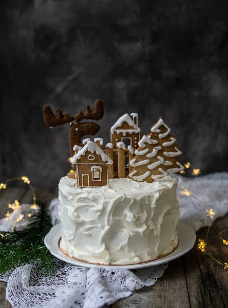Kue Natal dengan dekorasi roti jahe - kue dalam bentuk rumah dan pohon bersalju, rusa. Natal, kartu ucapan Tahun Baru. Latar belakang abu-abu dengan pohon Natal. Salin ruang . Stok Gambar