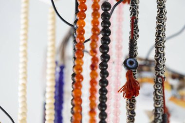 Gemstone ve inci kolyeler bir mücevher dükkanında asılı duruyor. Yanında da tekstil kablosu ve kırmızı püsküller var. Boncukların yakın görüntüsü var.