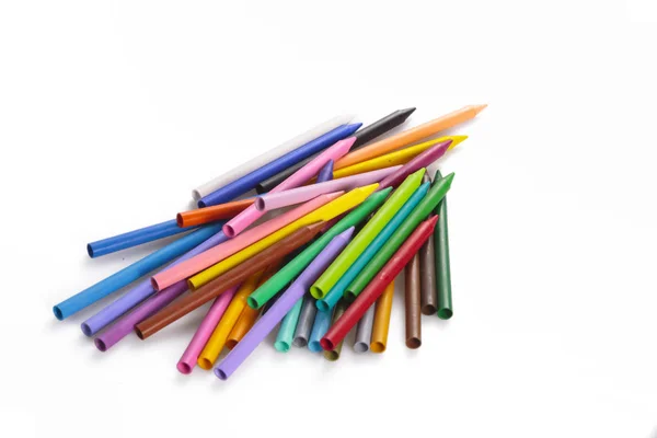 Sanat, eğitim ve yaratıcılık kavramında fotokopi alanı olan beyaz bir zemin üzerine yığılmış gökkuşağı renkli balmumu kalem yığını.