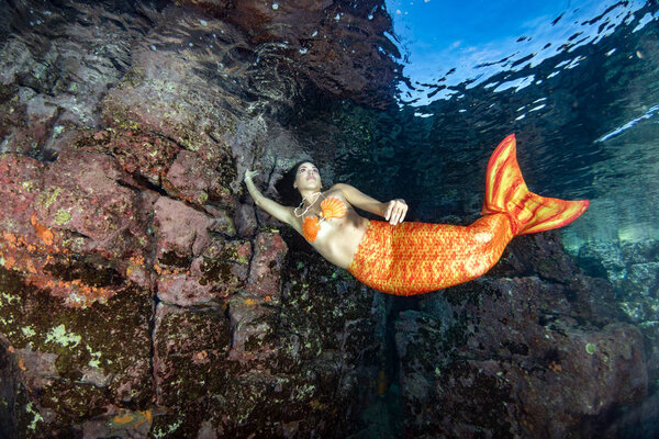 Mermaid swimming underwater in the deep blue sea