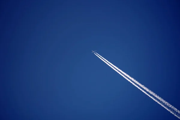 Trilhas de avião trilhas chemtrails no céu azul profundo — Fotografia de Stock
