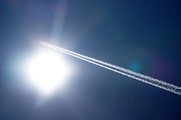 Літак стежить за хімічними стежками в глибокому блакитному небі — стокове фото