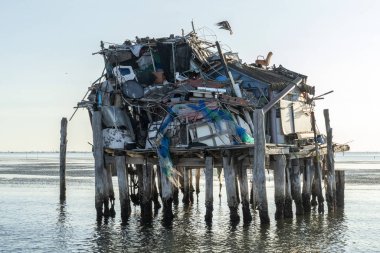 Plastik ve çöp dolu denizdeki Stilt evi