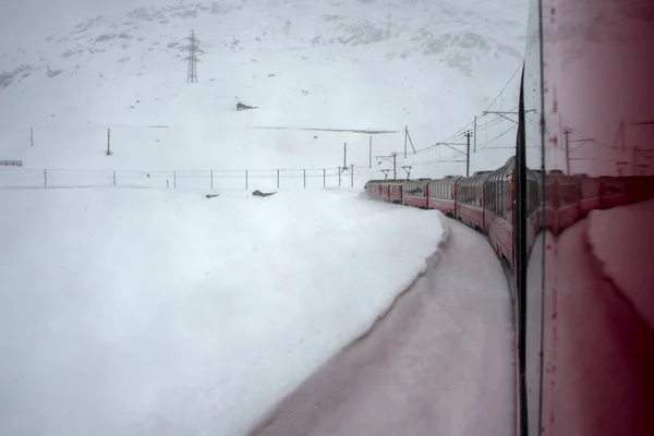 Красный поезд в снегу в швейцарских Альпах — стоковое фото