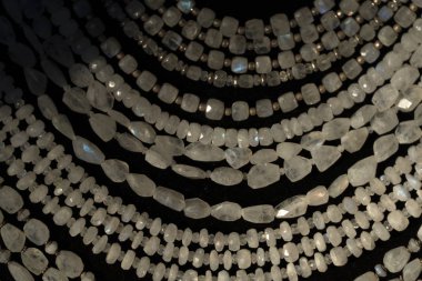 Gökkuşağı ay taşı yaka küpeleri bir mağazanın vitrininde mücevherler.