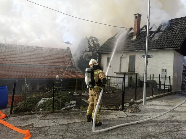 Hasič bojující s požárem v domě — Stock fotografie