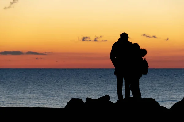 Lovers hugging in front of the sea at sunset — Stock Photo, Image