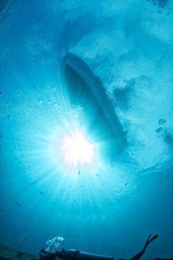 diving boat ship from underwater blue ocean with sun rays