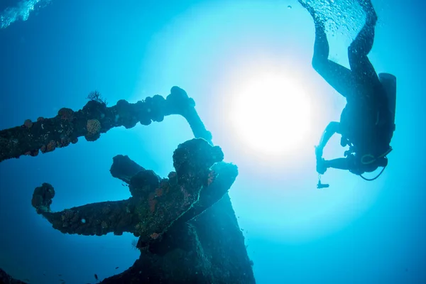 Taucher-Silhouette in der Nähe des Schiffswracks im blauen Meer — Stockfoto