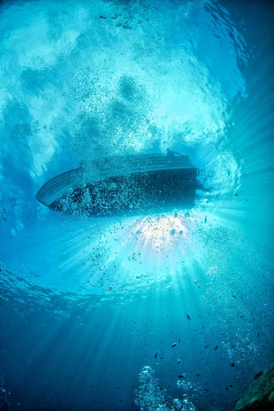 Diving boat ship from underwater blue ocean with sun rays — 스톡 사진