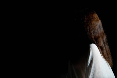 Siyah arka planda beyaz giyimli kadın profili. Yüz yok.