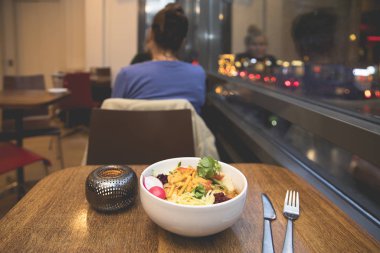 Lokantada arka planda insanların olduğu bir masada nefis, lezzetli bir salata tabağı manzarası.