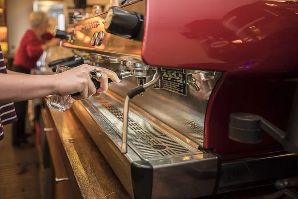 Kahve makinesini kahve yapmak için kullanırken çekilmiş bir fotoğraf. Kahve yapan kadın kafe çalışanı..