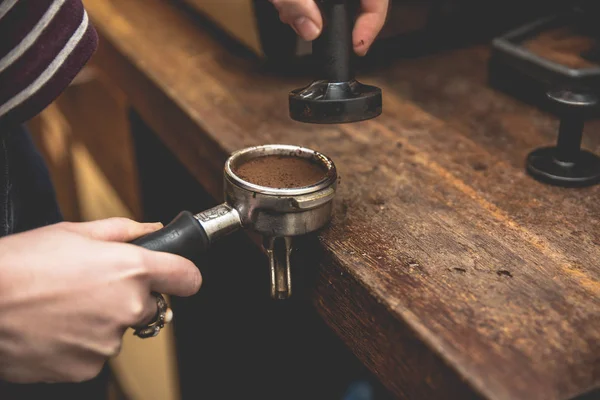 Bir espresso kahve barista holding portafilter ve kahve kurcalamak