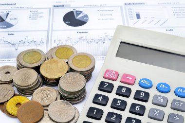 hesap makinesi ve beyaz kağıt yazılı grafik üzerinde sikke yığını