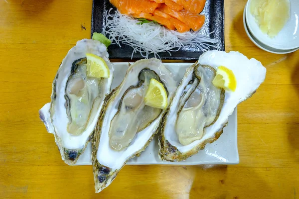 Rauwe oesters met citroen op witte plaat — Stockfoto