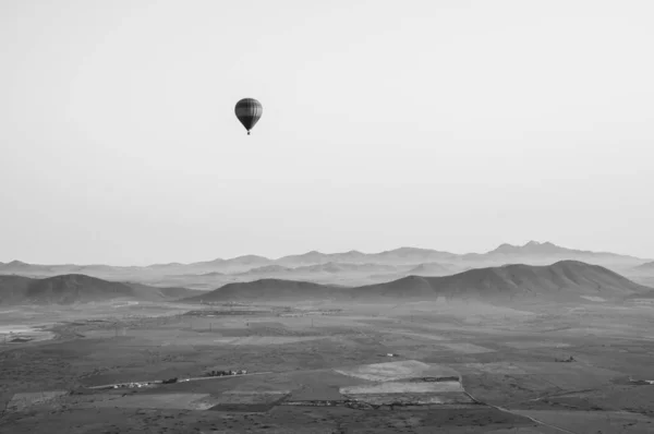 Fas 'ın yukarısındaki sıcak hava balonundan siyah beyaz bir resim. Uzaktaki güzel Atlas Dağları, gökyüzünde başka bir balonla. 