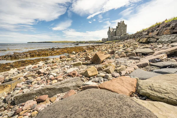 スコットランド高地のシンクレアベイにあるAckergill Towerの歴史的なホテル 背景に美しいと豪華な古い英国の邸宅とロッキービーチ スコットランドのウィックで曇りだが晴れた日 — ストック写真