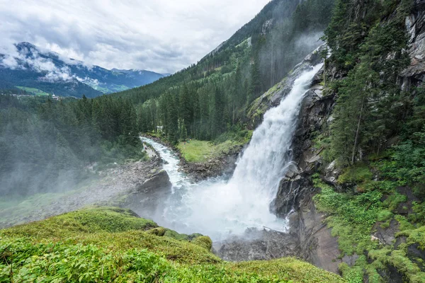 Salzburg yakınlarındaki Avusturya 'da bulutlu ve sisli bir günde Krimmml Şelaleleri ve kaynak orman manzarası. Avrupa 'nın en yüksek şelalesinde akan görkemli akarsu