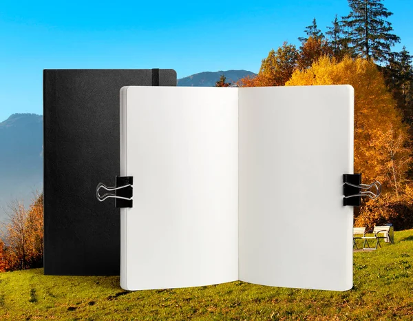 Notebook mockup on a beautiful autumn landscape background with forest, sky and mountains