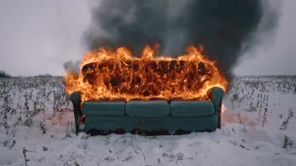 En soffa brinner på vinterfältet. Möblerna brinner. Begreppsvideo. Begreppet förstörelse, anarki, oordning, utbrändhet — Stockvideo
