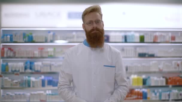 Retrato de un joven farmacéutico mira a la cámara y cruza sus palmas — Vídeo de stock