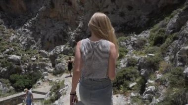 İnsanlar dağdan iner. Sona doğru giden kızın arkası görünüyor.