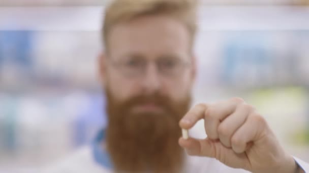 Slow motion. Portrait of a young doctor or pharmacist who shows a white pill and nods approvingly — Stock Video