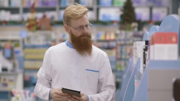 Young male pharmacist working in his large pharmacy. Placing medications inventory. Medicine, pharmaceutics, health care and people concept — Stock Video