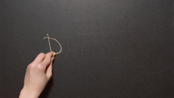 Danke. Una mano femenina izquierda escribe la palabra Danke con tiza amarilla en una pizarra negra — Vídeo de stock