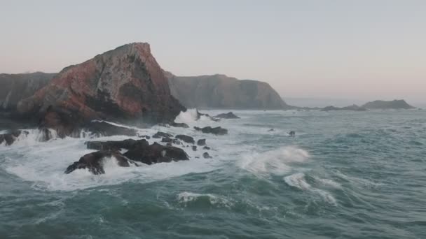 Colpo aereo di onde oceaniche che si infrangono costiera scogliera, ripida. L'onda marina si sta infrangendo sulle rocce. Aereo drone filmato cinematografico di belle scogliere al largo della costa del Portogallo sul tramonto . — Video Stock