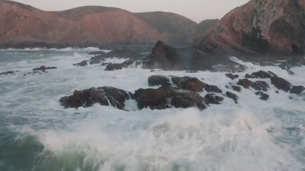 L'elicottero sorvola l'onda con la schiuma. L'onda marina si sta infrangendo sulle rocce. Aereo drone filmato cinematografico di belle scogliere al largo della costa del Portogallo sul tramonto . — Video Stock