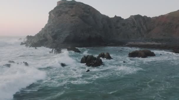 L'elicottero sorvola l'onda con la schiuma. L'onda marina si sta infrangendo sulle rocce. Aereo drone filmato cinematografico di belle scogliere al largo della costa del Portogallo sul tramonto . — Video Stock