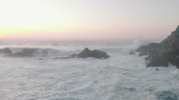 Запись с воздушного беспилотника красивых скал у побережья Португалии на Сансете. Морская волна бьется о скалы. Волны ломаются у подножия скал. Живописный вид на океан и горы — стоковое видео