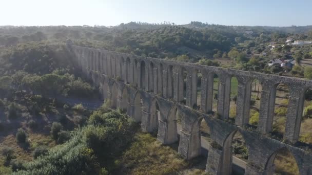 Древний акведук Пего близ Томара, Португалия. Веселый и счастливый парень и девушка идут вдоль акведука на встречу заката. Туристы переходят мост. Вид с воздуха — стоковое видео