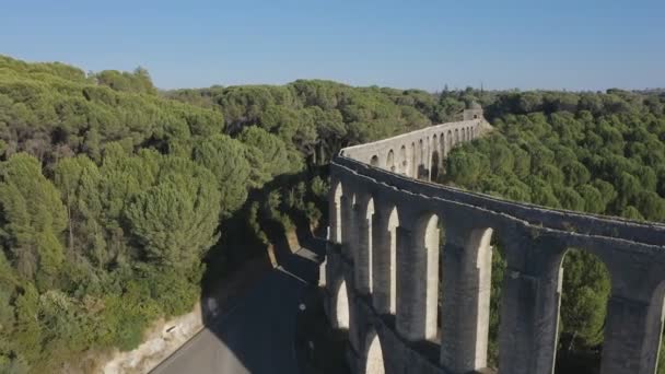 Antiguo acueducto de Pegoes cerca de Tomar, Portugal al atardecer. Drone desciende entre el acueducto y los árboles a la carretera — Vídeo de stock