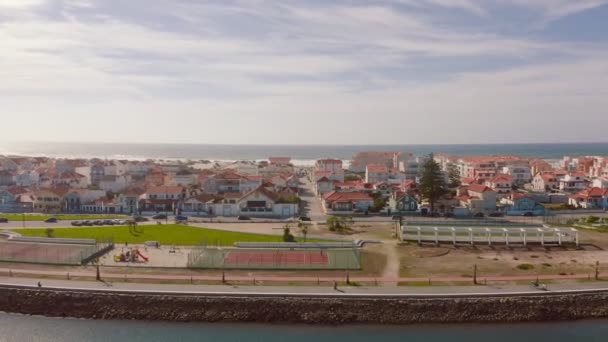 Portekiz 'in Costa Nova do Prado kentindeki geleneksel bir Portekiz balıkçı köyü üzerinde uçuş. Renkli ve çizgili evleri olan bir sokak. Bir dron Atlantik Okyanusu 'na köyün üzerinden uçuyor.. — Stok video