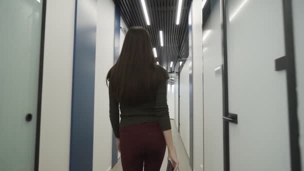 Piękna młoda dziewczyna idzie korytarzem w biurze z folderem dokumentów w rękach. Zwolnij trochę. Koncepcja: nowy biznes, komunikacja, kontakty, nowa umowa, sukces. — Wideo stockowe