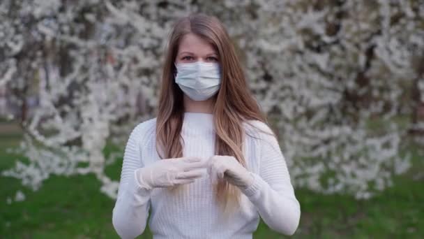 Конец изоляции и пандемии. Портрет кавказская девушка снимает защитные перчатки и маску для лица и улыбается в камеру. Блондинка, позирующая на улице в конце коронавирусного карантина. Весна . — стоковое видео