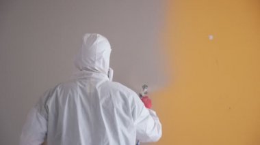 Dairenin tamiri. Profesyonel ressam duvarları beyaz boya sprey tabancasıyla boyuyor..