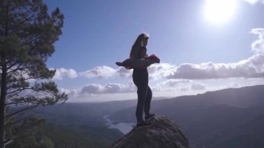 Uçurumun kenarında duran genç bir kadın silueti. Kaya zirvesinde başarılı olan kız.