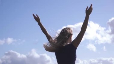 Güneşli bir günde mavi gökyüzüne doğru yükselen beyaz genç bir kızın arka görüntüsü. Yakın plan.