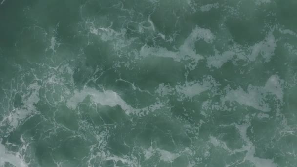大きな波が左から右へと回っています。青いターコイズブルーの海、波、ホワイトウォッシュの空中トップダウン4kドローンビュー。海の上の晴れた日。閉鎖 — ストック動画