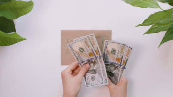 Les mains comptent les dollars, puis les mettent sur une enveloppe avec une inscription Loyer. La fille économise de l'argent pour le loyer . — Video