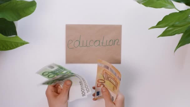 Les mains comptent l'argent, puis le mettent sur une enveloppe avec une inscription Éducation . — Video