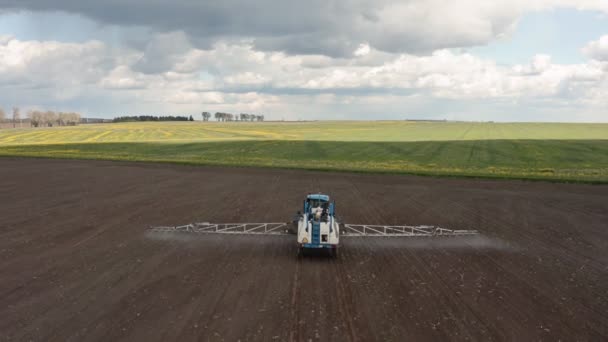 Luchtfoto van de sproeigrond en het jonge gewas van de trekker in het voorjaar in het veld. Verzorging en bescherming van de gewassen. — Stockvideo